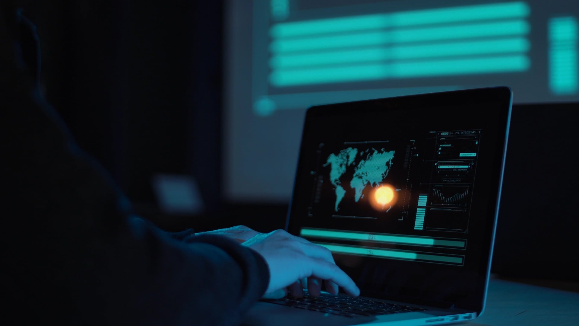cyberwarfare hands type on a computer in a dark room- there is a world map on the screen